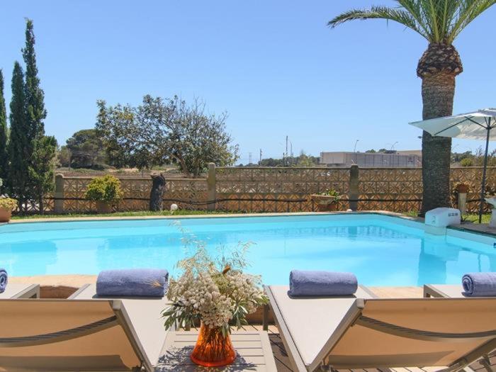 a large swimming pool with two chairs and an umbrella at Ca sa Padrina in Colonia Sant Jordi