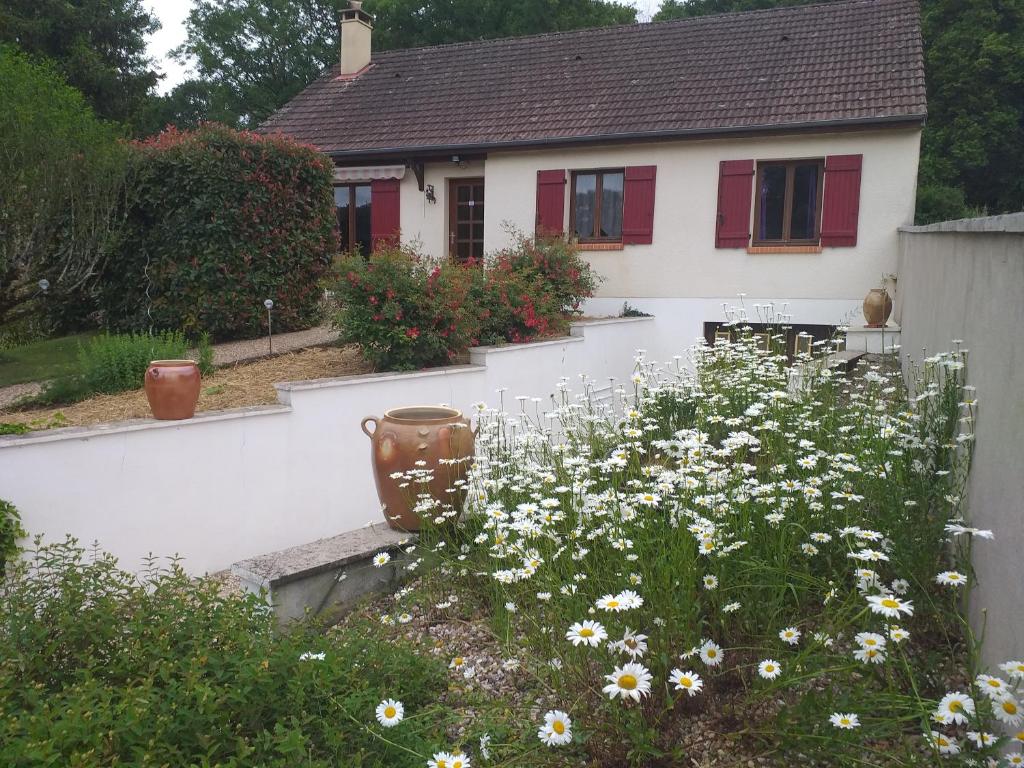 une maison blanche avec des fenêtres rouges et un jardin avec des fleurs dans l'établissement La Griotterie, à Saint-Amand-en-Puisaye
