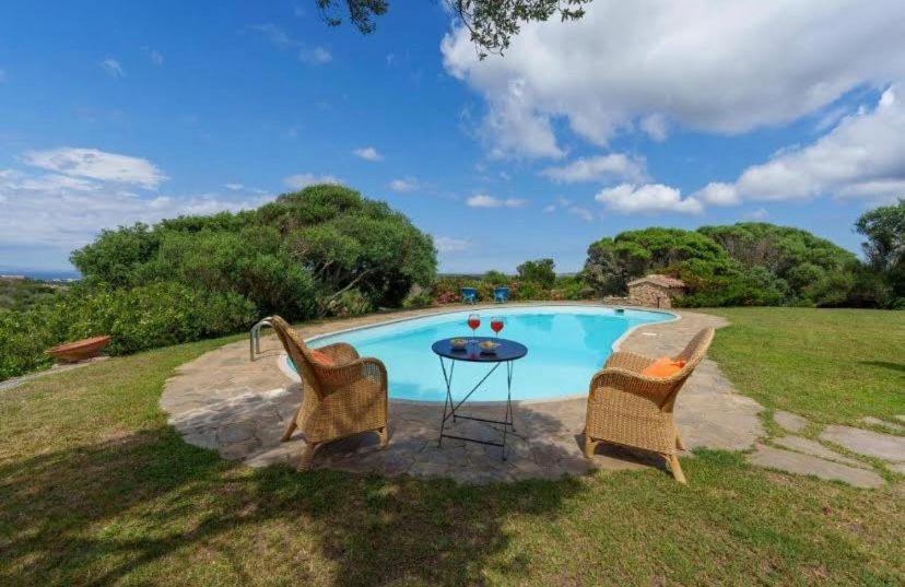 a pool with two chairs and a table next to it at VILLA VELA MARINA in Santa Teresa Gallura