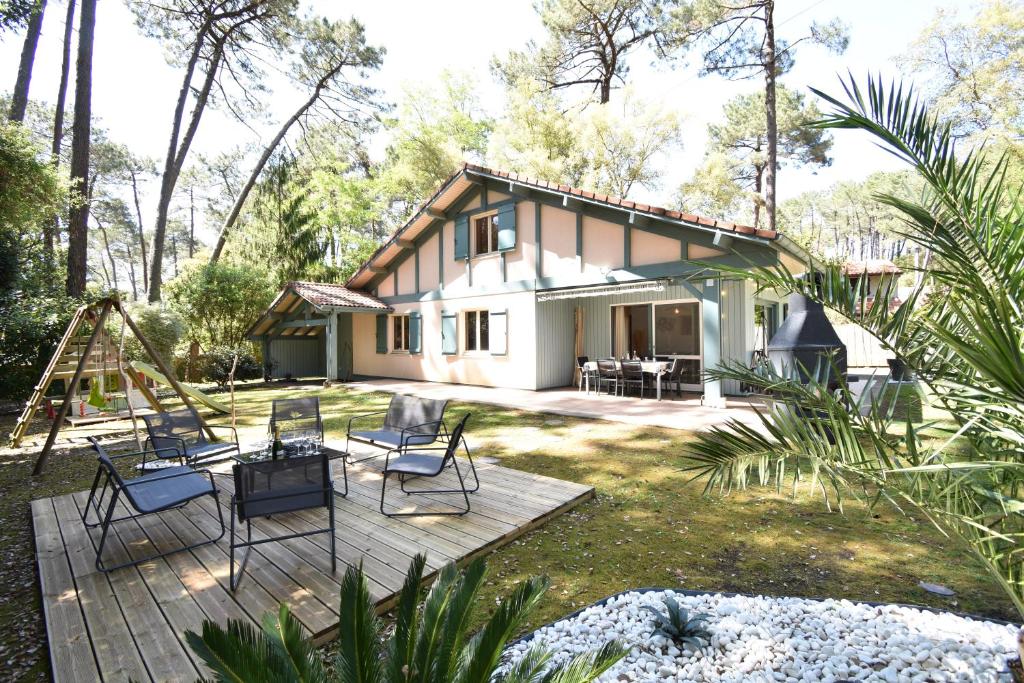 une maison avec une terrasse dotée de chaises et d'une balançoire dans l'établissement Marcassins - Hossegor belle villa landaise avec grand jardin location vacances, à Soorts-Hossegor
