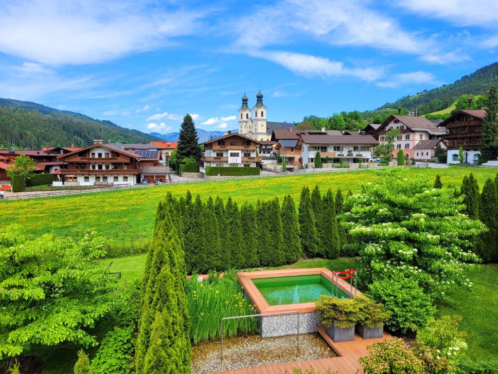 a resort with a swimming pool in a garden at Landhaus Tirol in Hopfgarten im Brixental