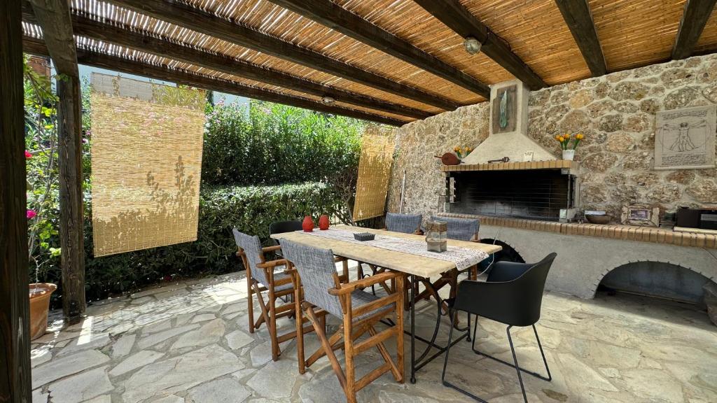 patio ze stołem, krzesłami i kominkiem w obiekcie Villa Serendipity Sea View w mieście Porto Heli