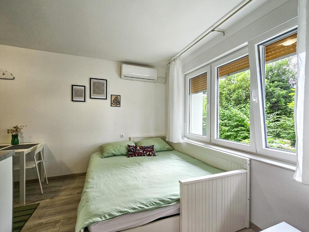 a small bedroom with a bed and two windows at Marigold in Rijeka