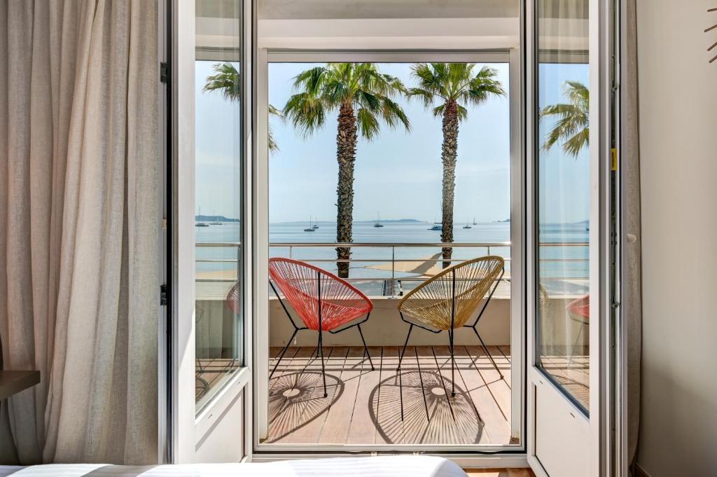 2 sillas sentadas en un balcón con palmeras en Le Bor en Hyères