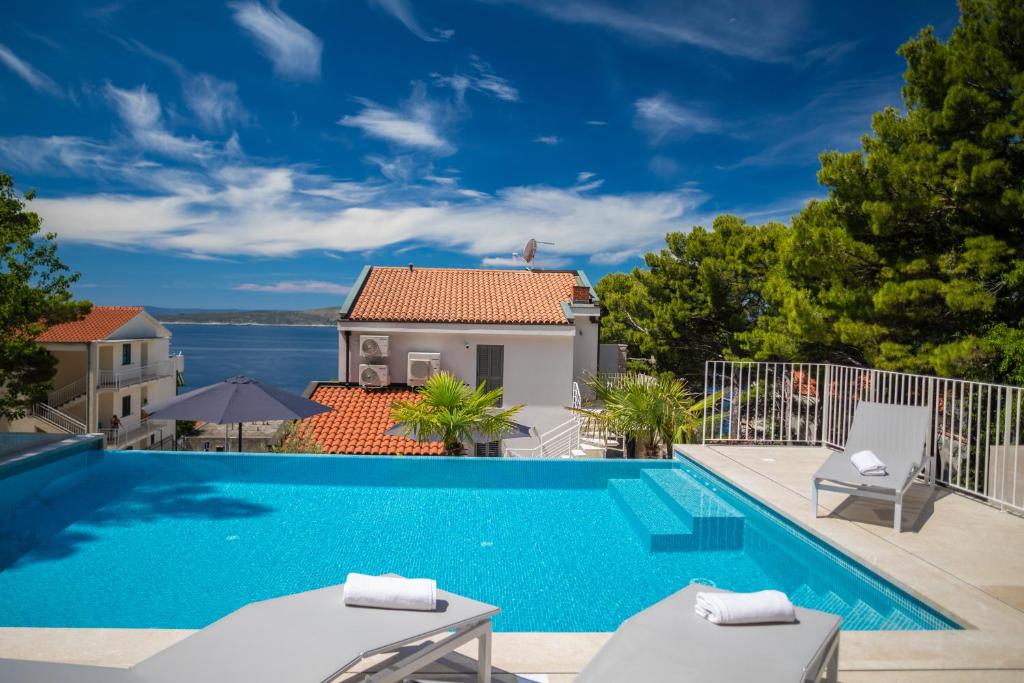a swimming pool with two chairs and a house at Villa Brela apartments in Brela