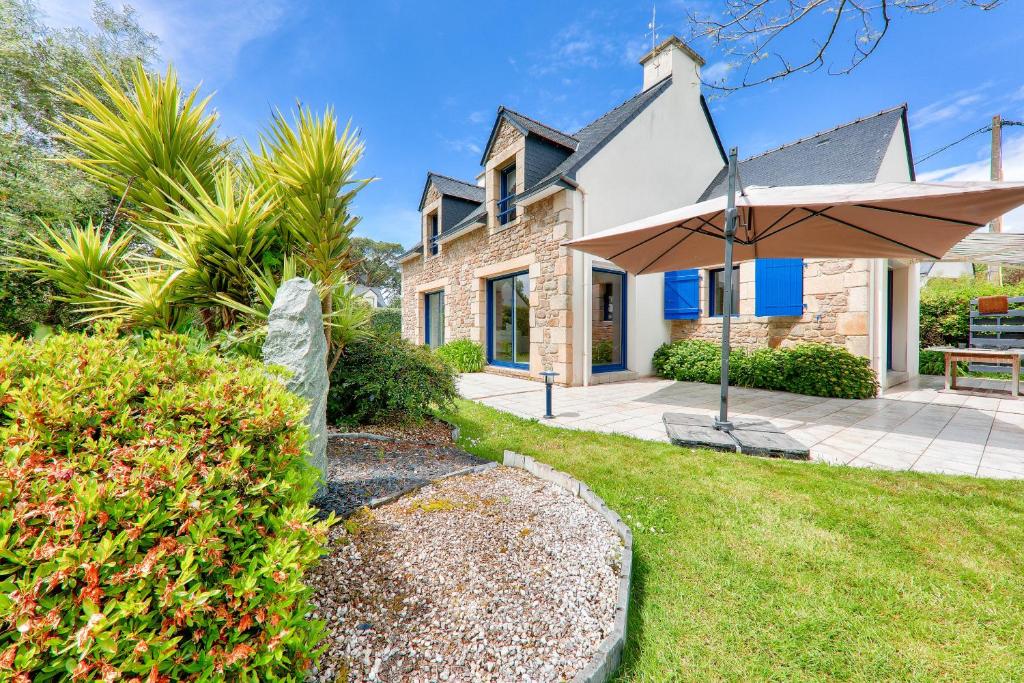 a house with a patio and an umbrella at Maison de pierre pour 8 avec beau jardin in Saint-Gildas-de-Rhuys