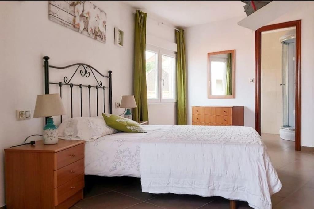 a bedroom with a bed and a dresser and windows at Casa roja in Camariñas