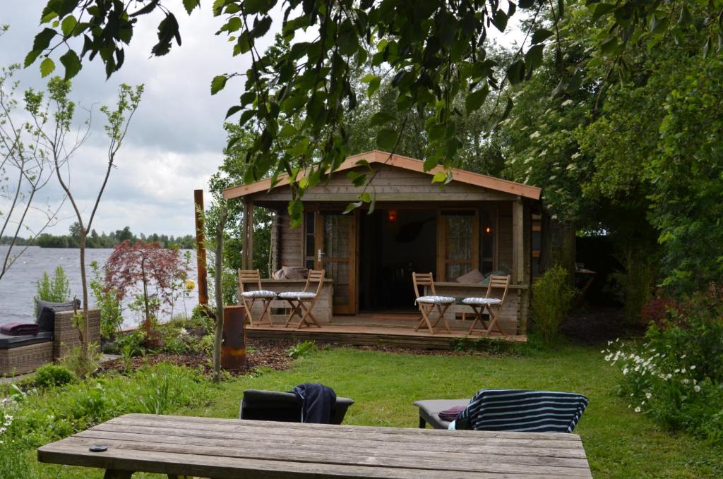 a small cabin with a table and chairs in the grass at Luxury Experience in Off The Grid Lodge at an Amazing Lake Vinkeveense Plassen in Vinkeveen