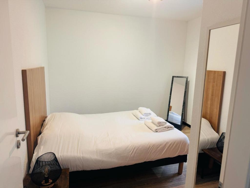- une petite chambre avec un lit et un miroir dans l'établissement KOSY Appart'Hôtel 7ème Art, à Saint-Avold