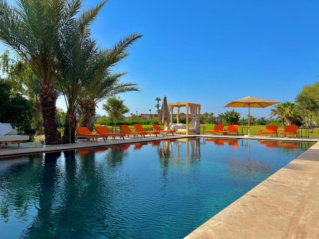 uma piscina com cadeiras e guarda-sóis num resort em Pavillon du Golf -Palmeraie suites em Marraquexe