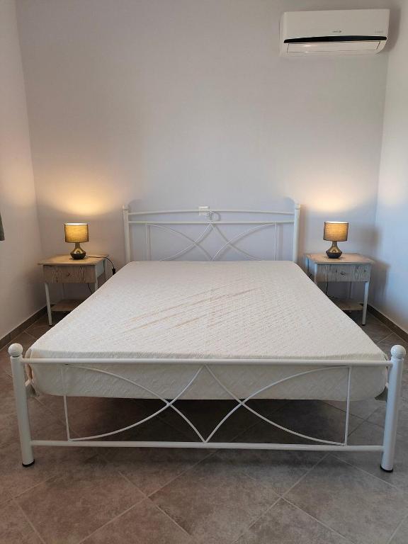 a bedroom with a white bed with two side tables at Pefki Apartment 9 in Artemísion