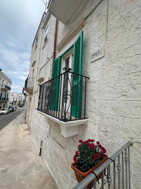 a window with green shutters and a flower pot on a building at Angel House in Locorotondo