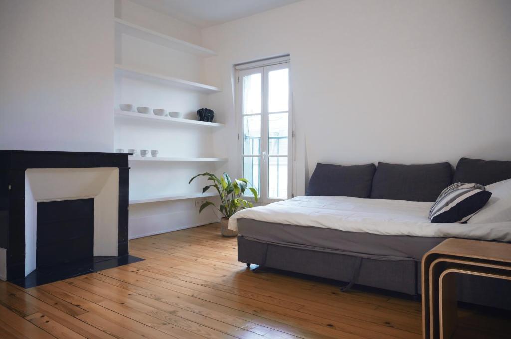 - un salon avec un lit et une cheminée dans l'établissement Charmant appartement au coeur de paris 6ème, à Paris