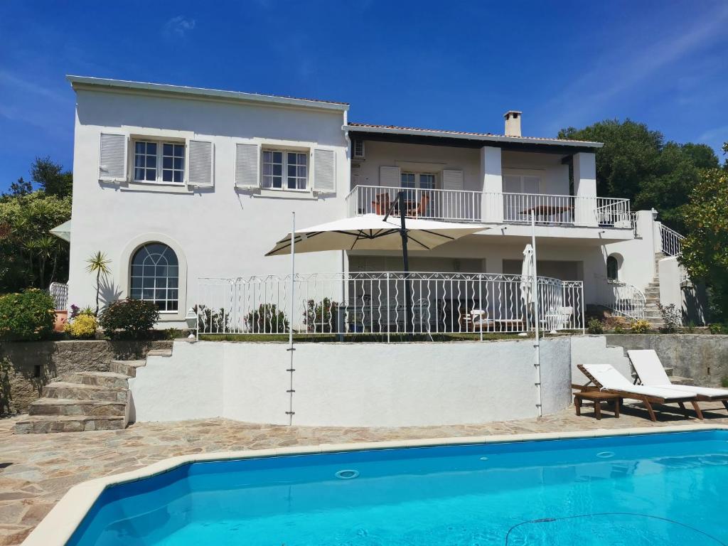 eine Villa mit einem Pool vor einem Haus in der Unterkunft Villa Via serena in Ajaccio