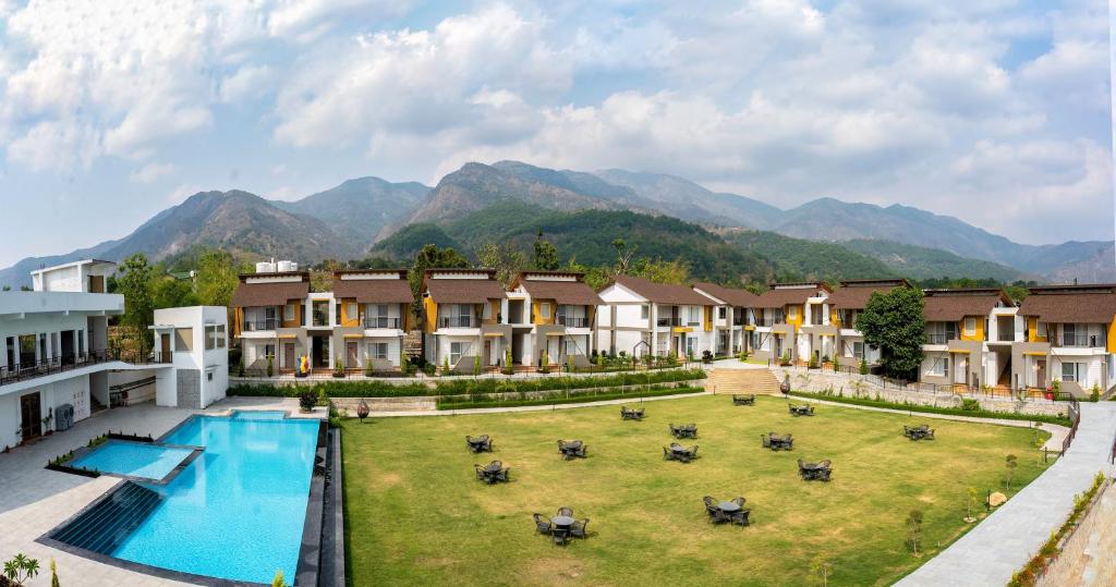 une image d'un complexe avec une piscine et des montagnes dans l'établissement Evara Spa & Resort, à Rāmnagar