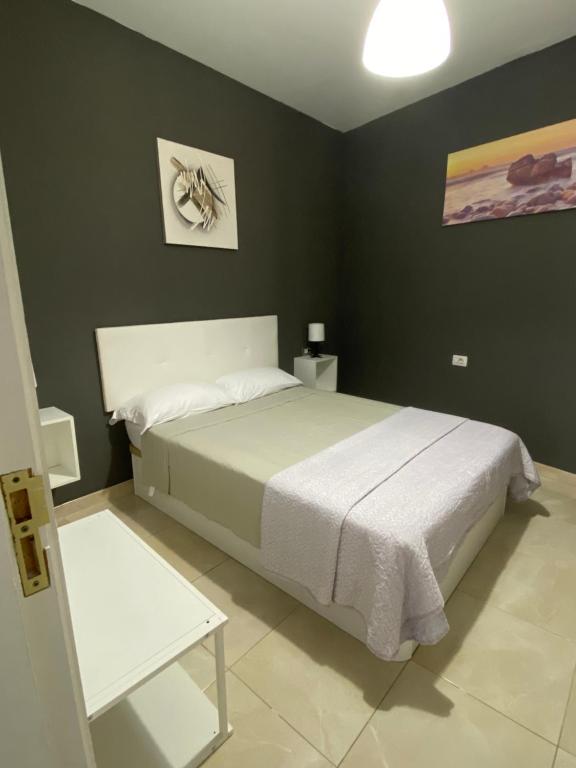 1 dormitorio con cama blanca y paredes negras en DELUXE ROOM IN APARTMENT SHARED in Los Cristianos Playa HabitaciónSTANZA air-conditioned, en Arona