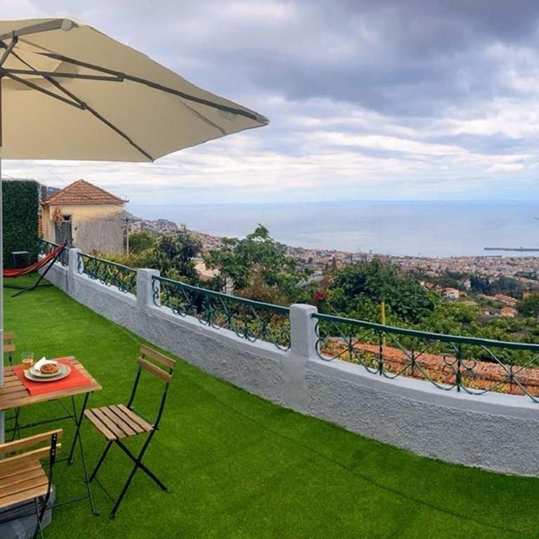 a balcony with a table and chairs and an umbrella at Casa D'Avó Filó in Funchal