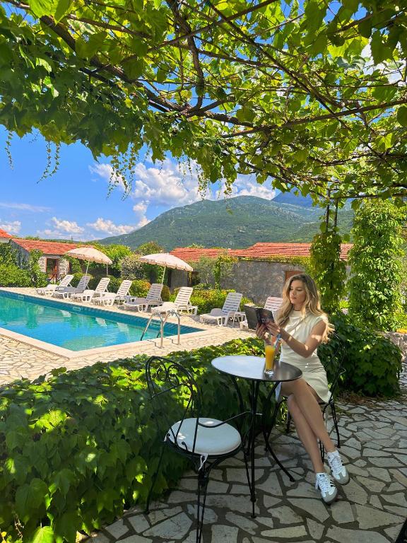 a woman sitting at a table next to a pool at Hotel Opera Jaz in Budva