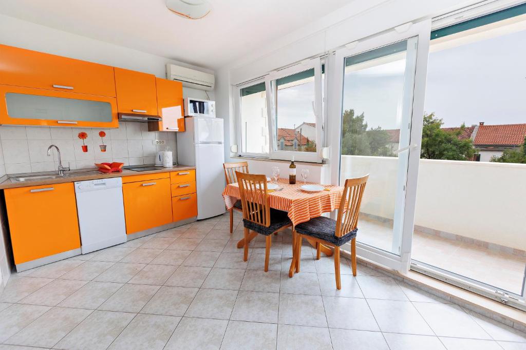 a kitchen with orange cabinets and a table and chairs at Apartments Baričević in Bol