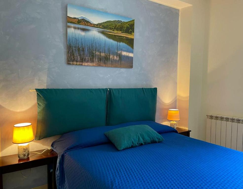 a bedroom with a blue bed with two lamps at Al Palmento in Galati Mamertino
