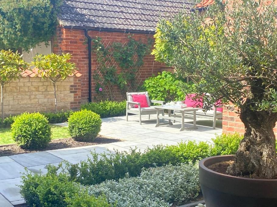eine Terrasse mit einem Tisch und einem Stuhl im Garten in der Unterkunft Orchard Cottage in Lincolnshire