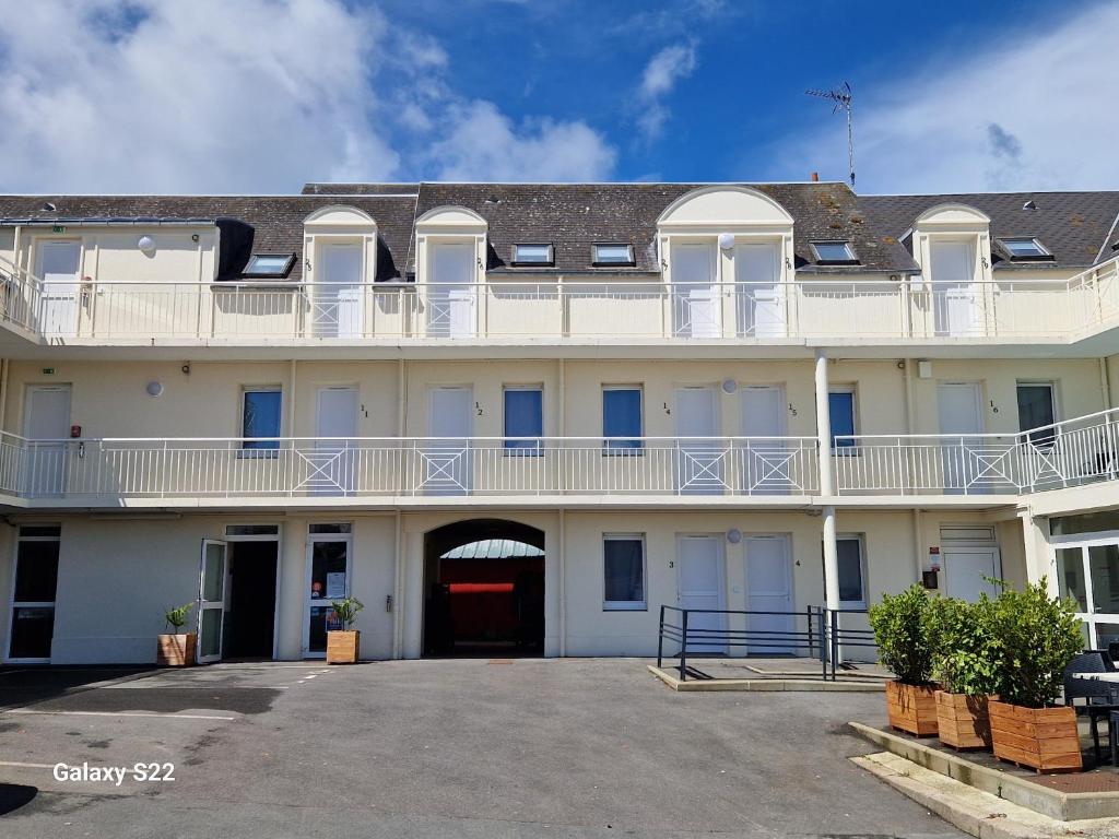 a large white building with a balcony on it at Hotel Eisenhower (ex King Hôtel) in Port-en-Bessin-Huppain