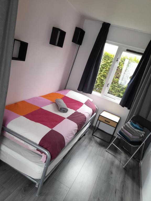 um quarto com uma cama com um cobertor listrado e uma janela em Chalet 4 persoons em Anloo