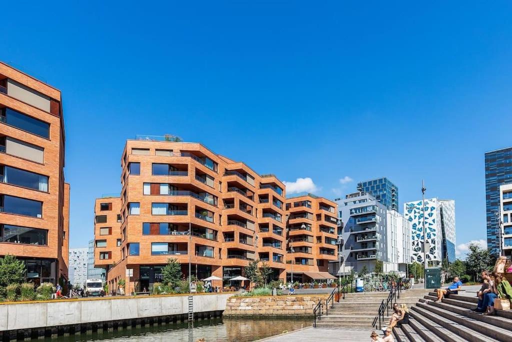a building in a city next to a river with buildings at Superb apartment by Opera house in Oslo