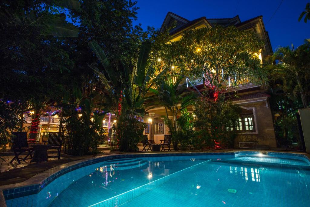 - une piscine en face d'une maison la nuit dans l'établissement Le Tigre Hotel, à Siem Reap