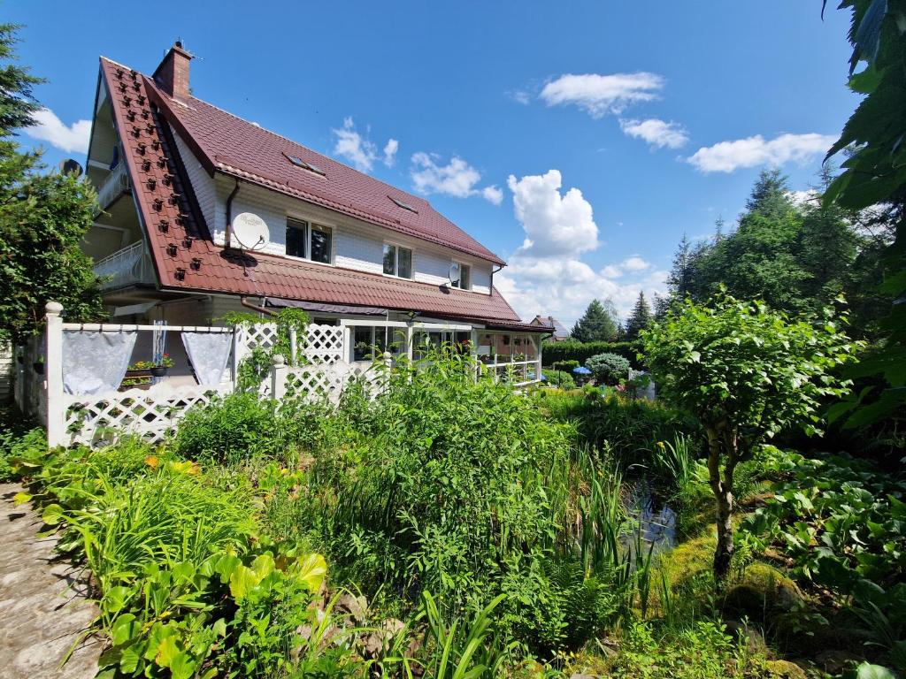 una casa con techo rojo y jardín en Haus Oberberg - Pokoje Ozonowane, en Wilkasy