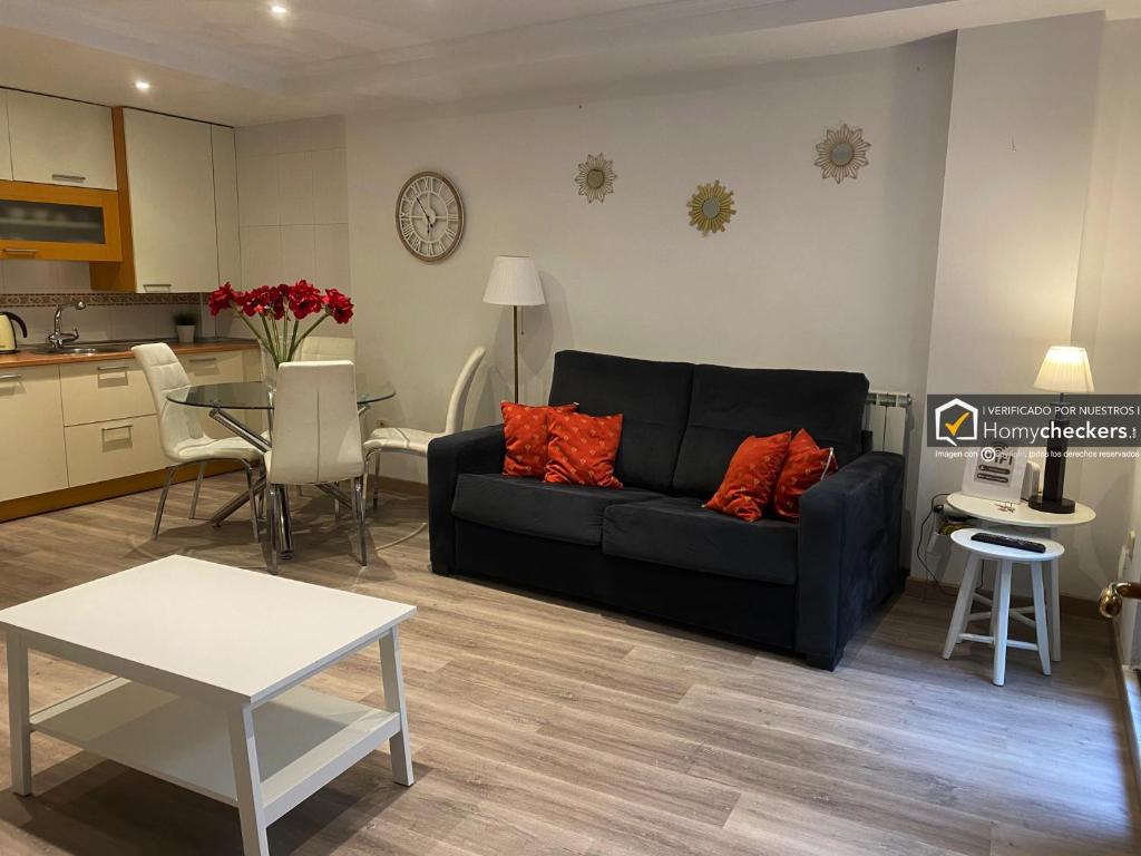 a living room with a black couch and a kitchen at Apartamento Cervantes Centro Historico in Salamanca