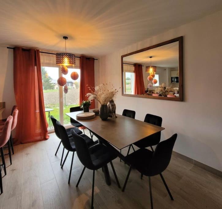 une salle à manger avec une table, des chaises et un miroir dans l'établissement Maison familiale et cosy - Entre lac et montagne, à Doussard