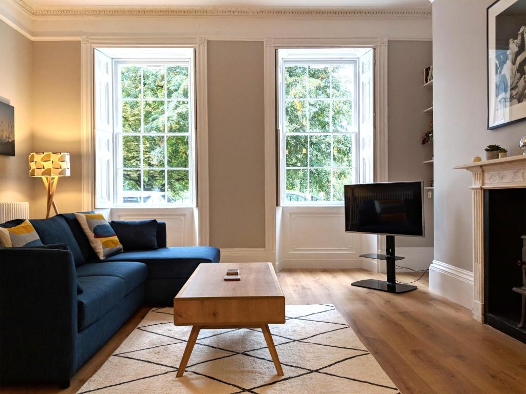 a living room with a blue couch and a tv at Park View Ground Floor 1 Bed Apt in Bath