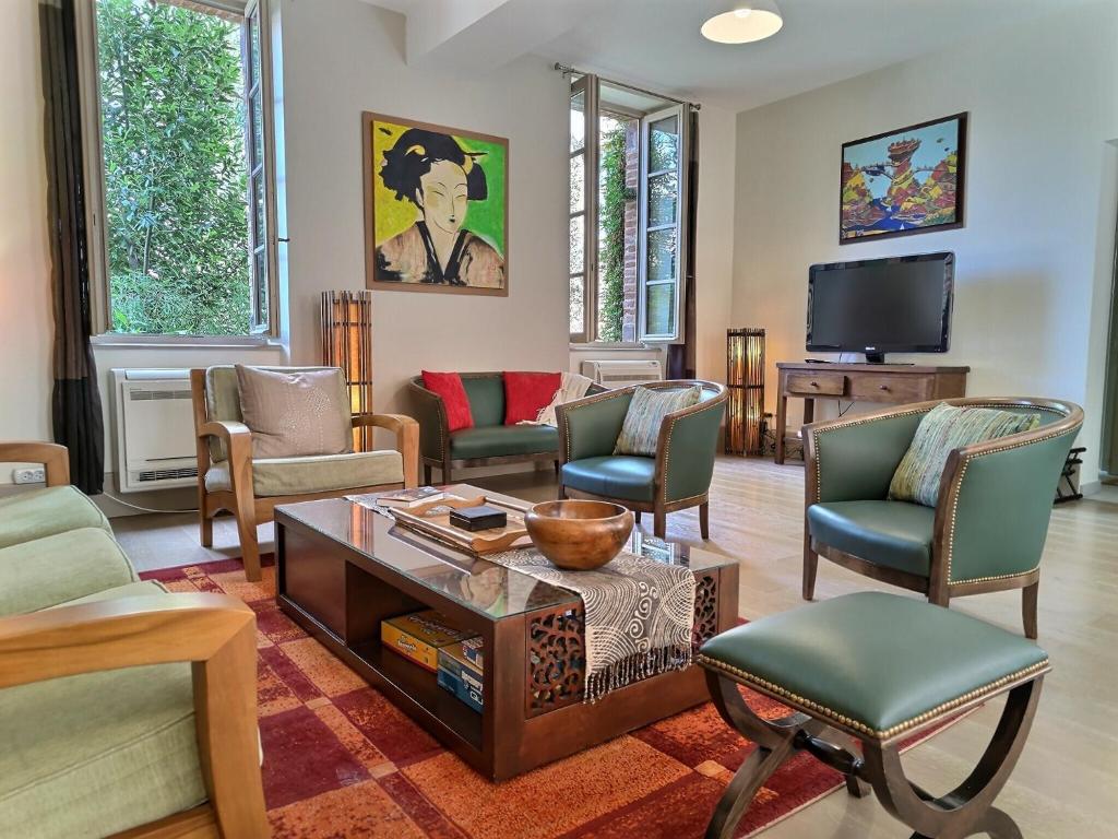 - un salon avec des chaises, une table et une télévision dans l'établissement La Maison des 2 Ponts Clim Centre, à Albi