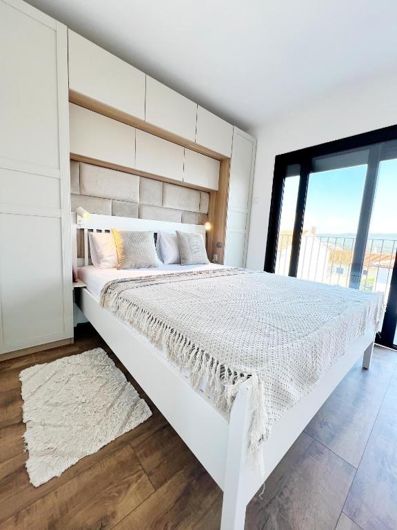 a white bed in a bedroom with a large window at Meldaria Residence in Krk