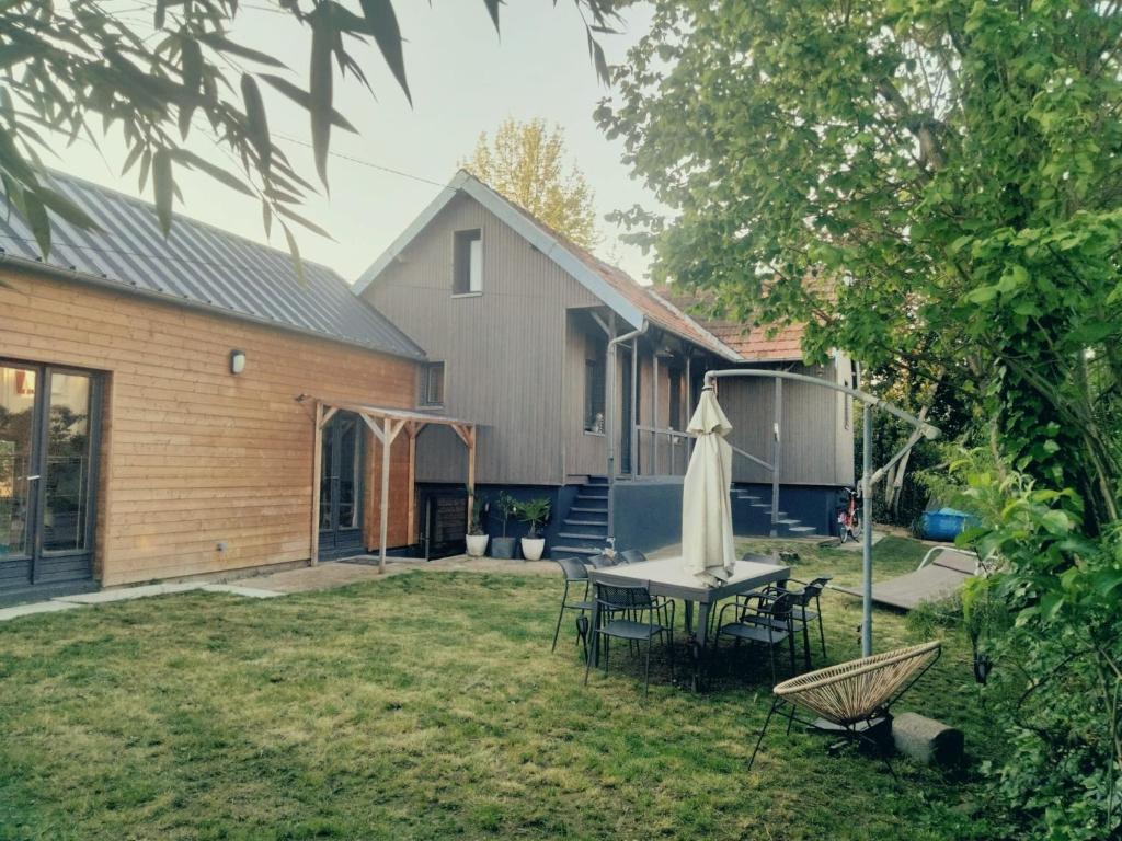 une arrière-cour avec une table, des chaises et un parasol dans l'établissement MAISON ATYPIQUE EN BOIS 2 NIVEAUX 7,5km du circuit 24h, au Mans