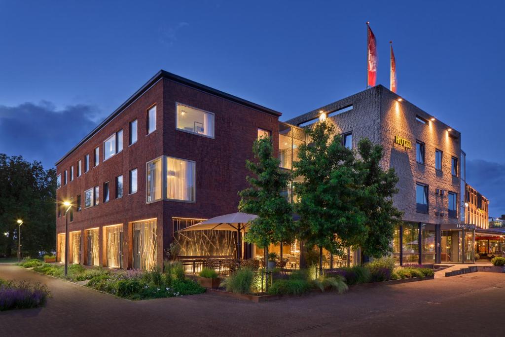 ein großes Backsteingebäude mit einem Baum davor in der Unterkunft Hotel Restaurant Grandcafé 't Voorhuys in Emmeloord