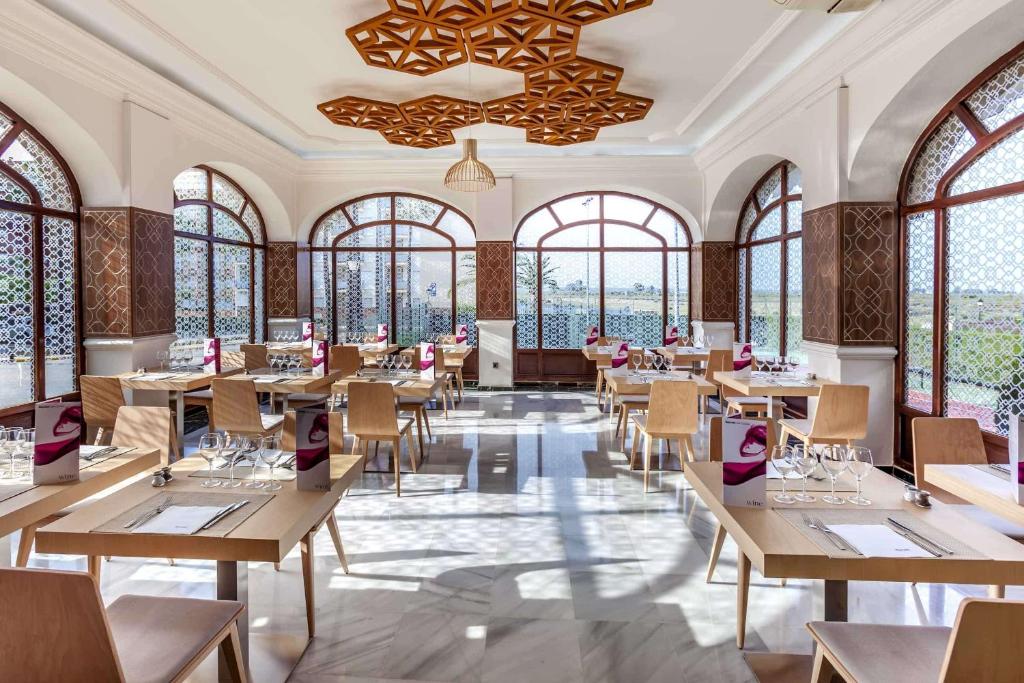 a restaurant with tables and chairs and windows at Barceló Isla Canela in Isla Canela