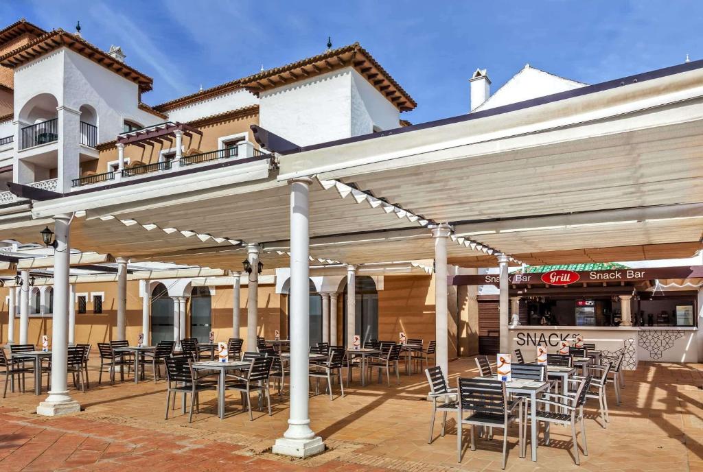 a patio with tables and chairs in front of a building at Barceló Isla Canela in Isla Canela