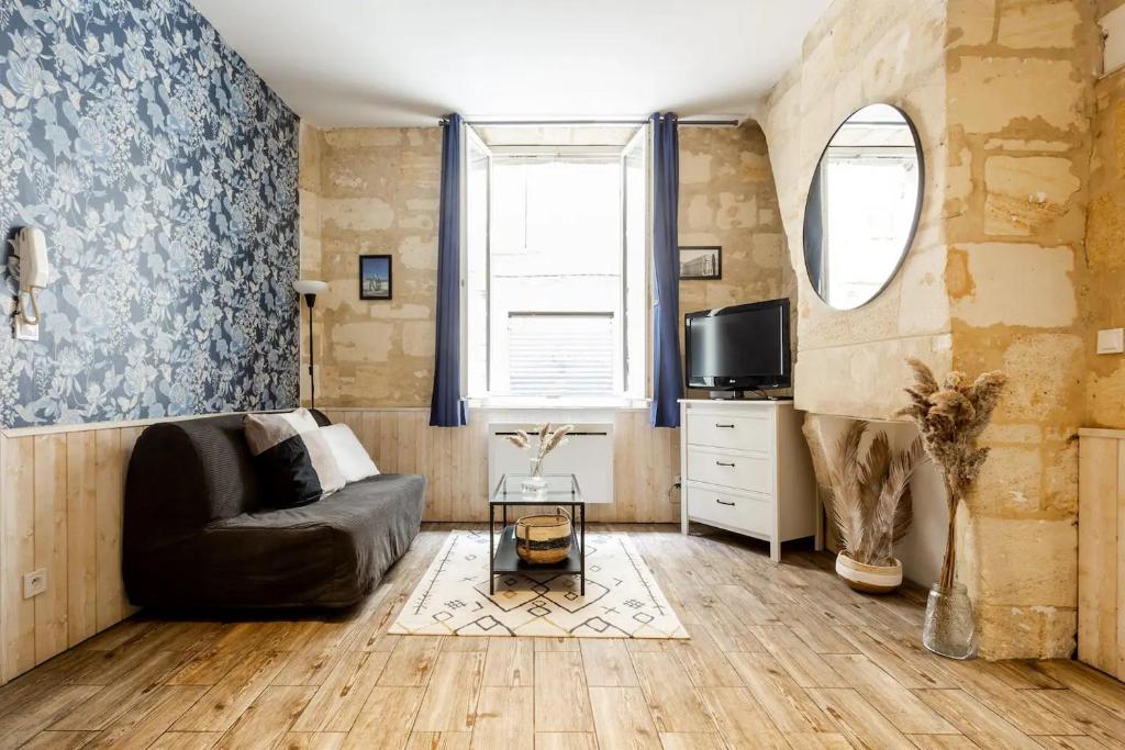 een woonkamer met een bank en een tv bij Lurbe Bleue - Bordeaux central et calme in Bordeaux