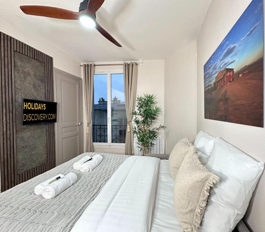 a bedroom with a white bed with a ceiling fan at 1562 - Cosy Montmartre in Paris Olympic Games 2024 in Paris