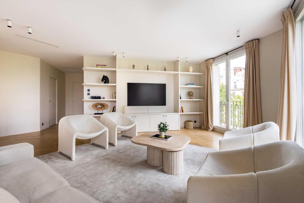 Il comprend un salon doté d'un mobilier blanc et d'une télévision à écran plat. dans l'établissement Elegant apartment - 3B 6P - Eiffel Tower, à Paris