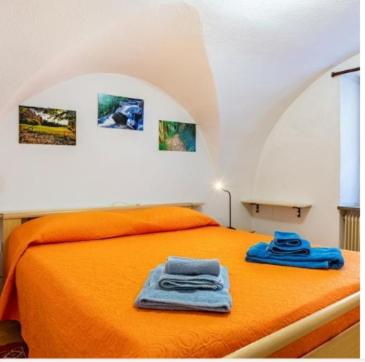 een slaapkamer met een oranje bed met 2 handdoeken erop bij App. Valentina in Segonzano