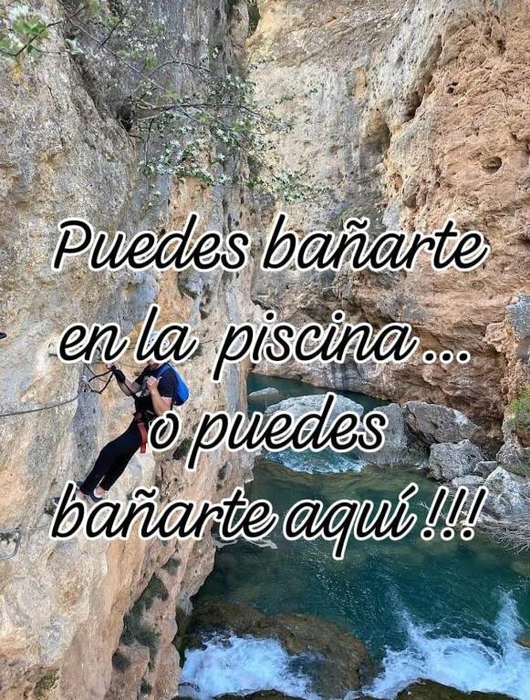 a person is rappelling over a river on a cliff at Aventura & Relax Cabañas Peña la Higuera in Villalba de la Sierra