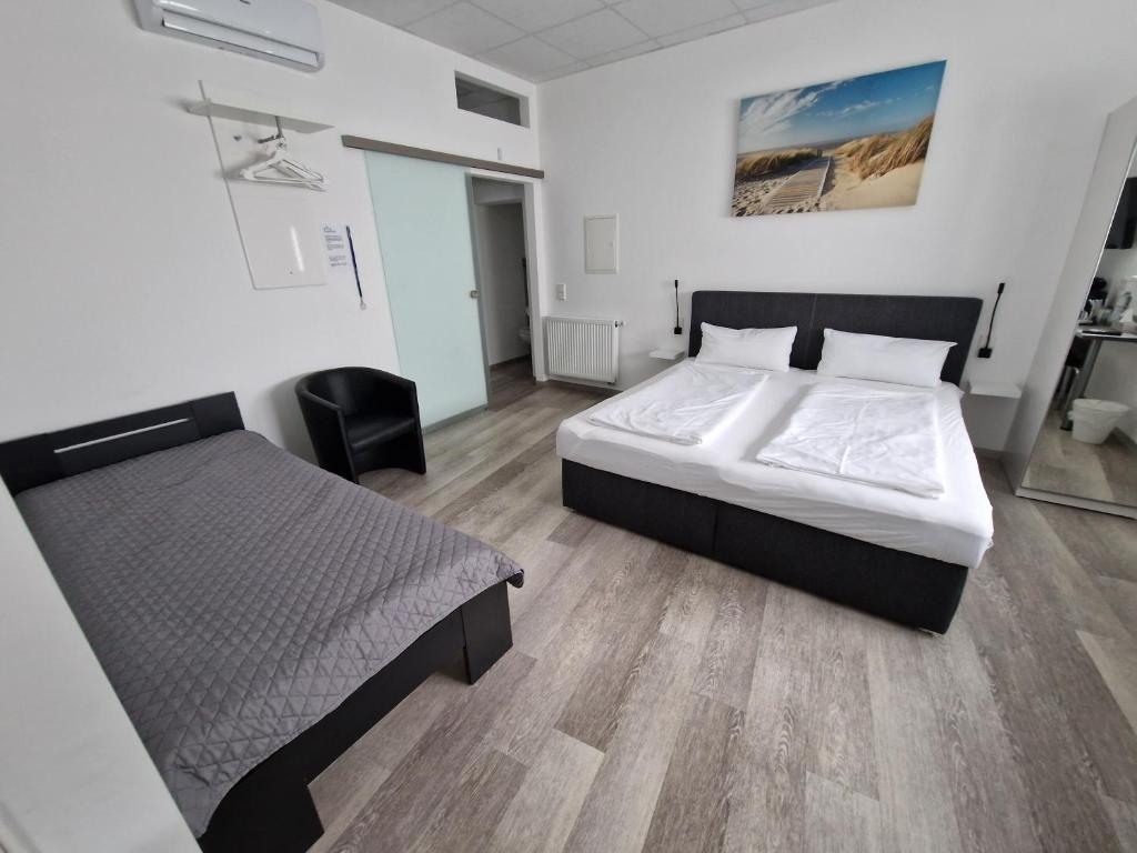 um quarto com duas camas e uma cadeira. em Hotel FeWo-HM em Ramstein-Miesenbach