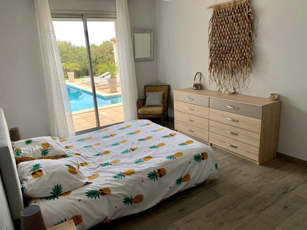 une chambre avec un lit et une commode et une piscine dans l'établissement Maison dans la garrigue, à Beaulieu