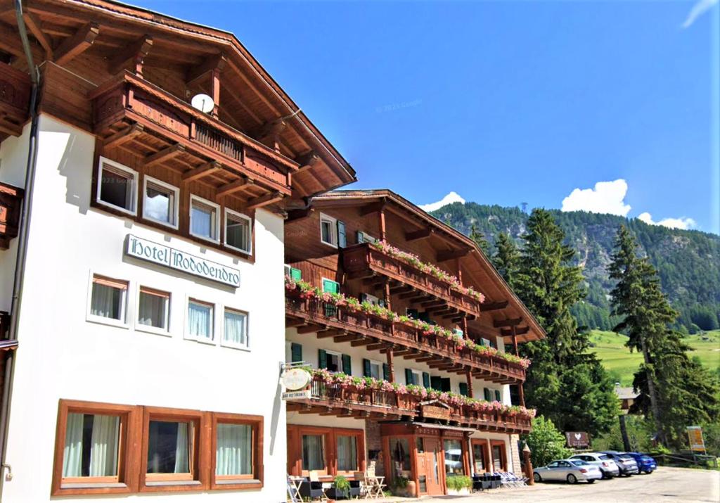 een hotel in de bergen met auto's geparkeerd bij Hotel Rododendro Val di Fassa in Campitello di Fassa
