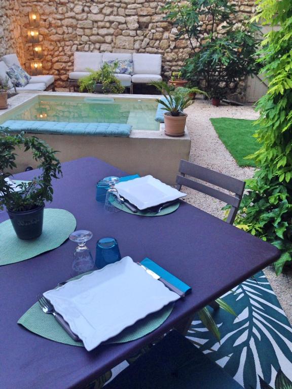 une table violette avec des serviettes blanches dessus à côté d'une piscine dans l'établissement La Capucine, à Cavaillon