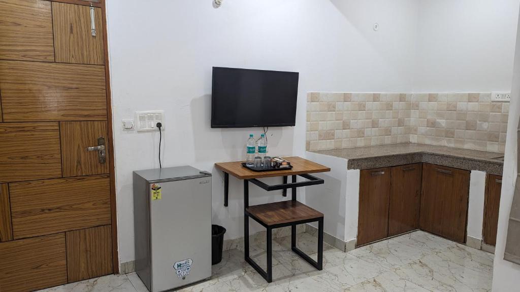 a kitchen with a small table and a television on the wall at Hotel Prime Chhatarpur in New Delhi