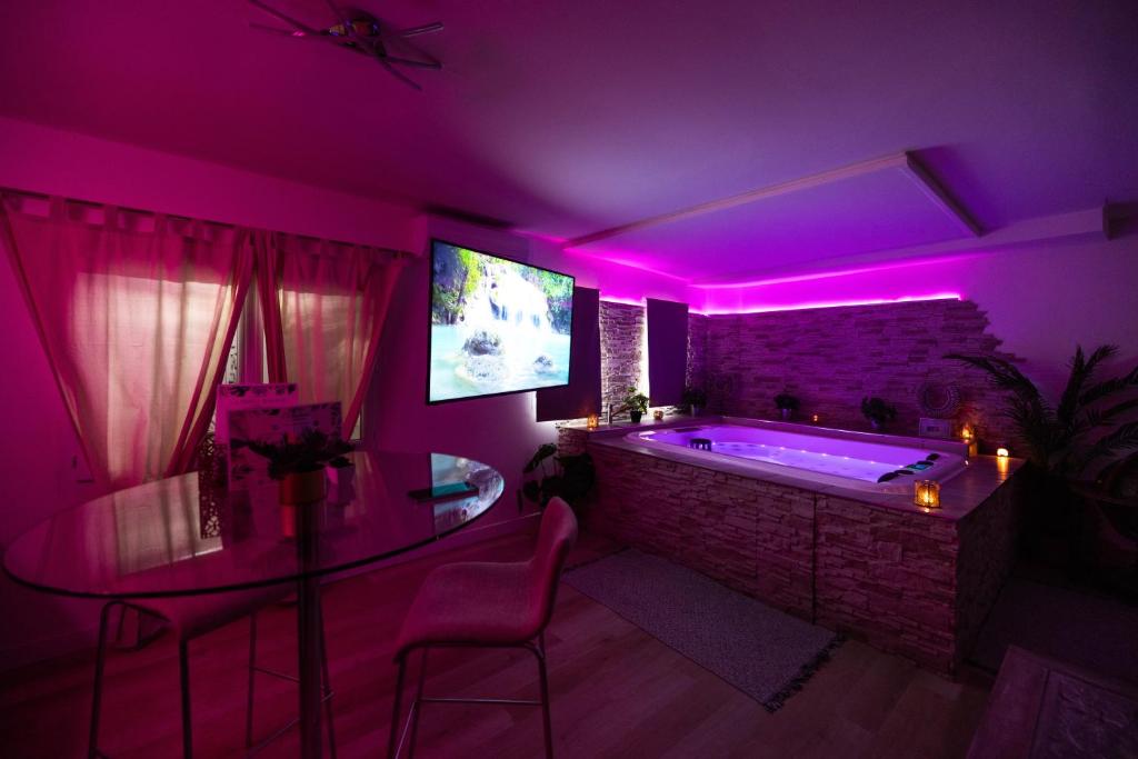 a purple room with a tub with a tv and pink lighting at Suite and Spa la Perla Bianca in Grabels